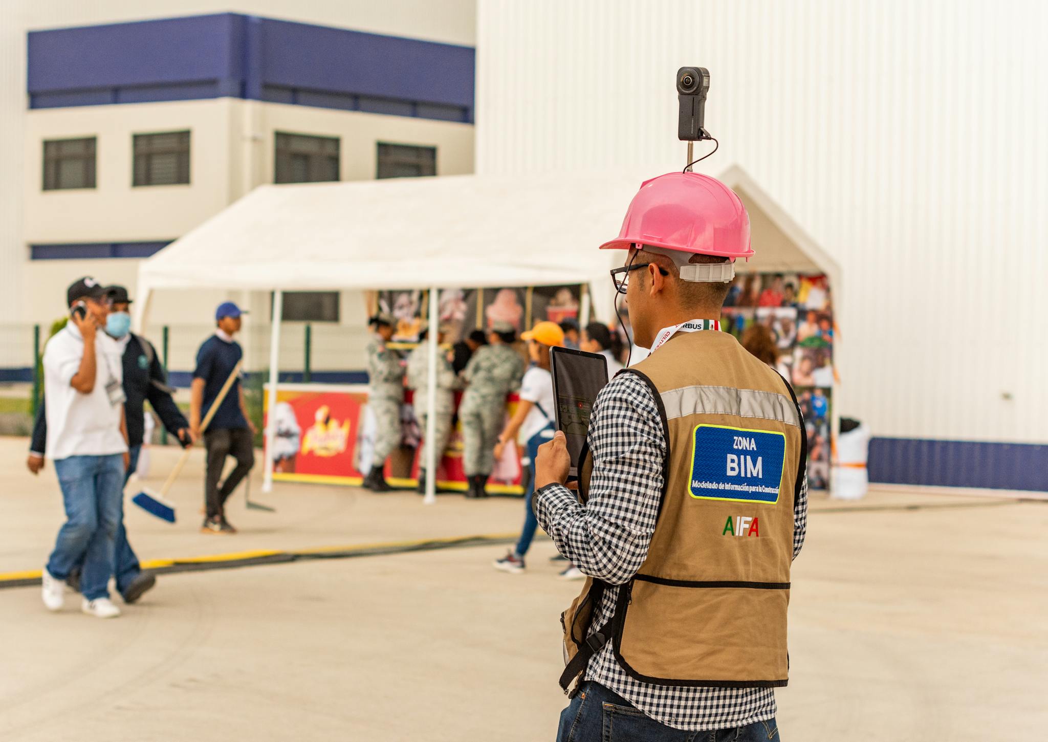 A construction worker with a tablet and camera inspects a site, using modern technology for documentation.